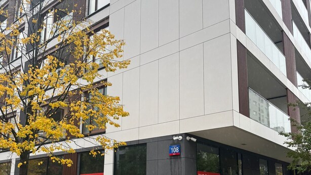 Ein modernes Gebäude mit großen Fenstern und einem Schild mit der Aufschrift 'WYNAJMÉ'.