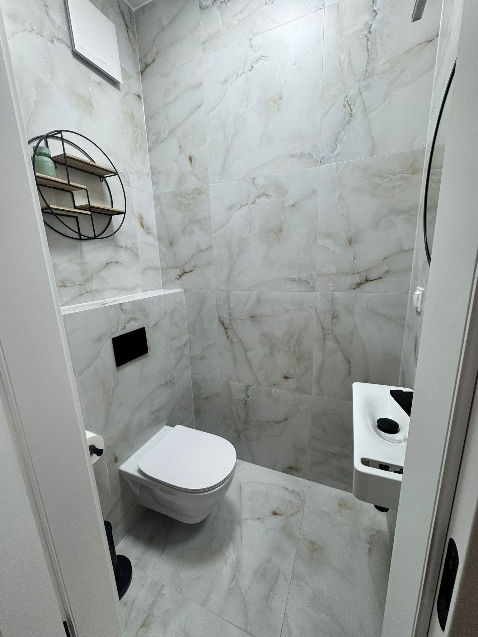 Une salle de bain avec des toilettes, une douche et un mur en marbre.