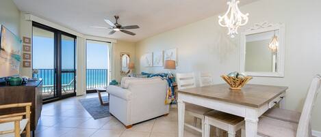A spacious living area with a dining table, a sofa, and a balcony with a view.