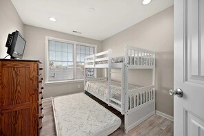Een kinderkamer met stapelbedden, een houten dressoir en een televisie.