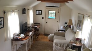 A cozy, well-lit room with a wooden ceiling, a dining area with a table and chairs, a sofa, and a small side table with a lamp. - Charming cottage on goat farm in picturesque Westport (Westport)