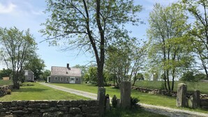 A stone wall, a grassy lawn, and a house with a chimney. - Charming cottage on goat farm in picturesque Westport (Westport)