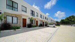 A modern multi-story residential building with a paved driveway and parked cars. - Sorrento 10 3 Bedroom Villa (Gibbes)