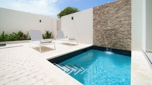 A swimming pool with two lounge chairs and a stone wall. - Sorrento 10 3 Bedroom Villa (Gibbes)
