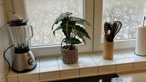 A kitchen with a blender, a potted plant, a utensil holder, and a Samsung refrigerator. - 300 MBit WLAN | directly at Marienplatz | first floor | subway (Stuttgart)