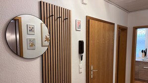 A hallway with a wooden panel wall, a round mirror, and a door with a keyhole. - 300 MBit WLAN | directly at Marienplatz | first floor | subway (Stuttgart)