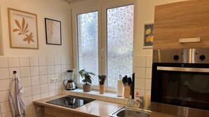 A modern kitchen with a built-in oven, a sink, and a window with frosted glass. - 300 MBit WLAN | directly at Marienplatz | first floor | subway (Stuttgart)
