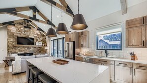 A modern kitchen with a large island, wooden cabinets, and a stone backsplash. - 37 Alcove 3 Bedroom Townhouse (Keystone)
