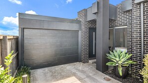A modern house with a large garage door, brick walls, and a potted plant. - Bright 2-bed Glenroy Home With Courtyard (Melbourne)