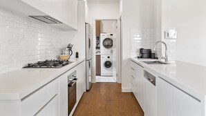 A modern kitchen with white cabinetry, a built-in stove, and a dishwasher. - Bright 2-bed Glenroy Home With Courtyard (Melbourne)