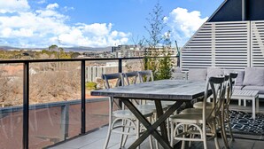 Een terras buiten met een tafel en stoelen, een bank en uitzicht op een stadsbeeld.