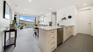 Een moderne keuken met een groot eiland, houten keukenkastjes en uitzicht naar buiten.