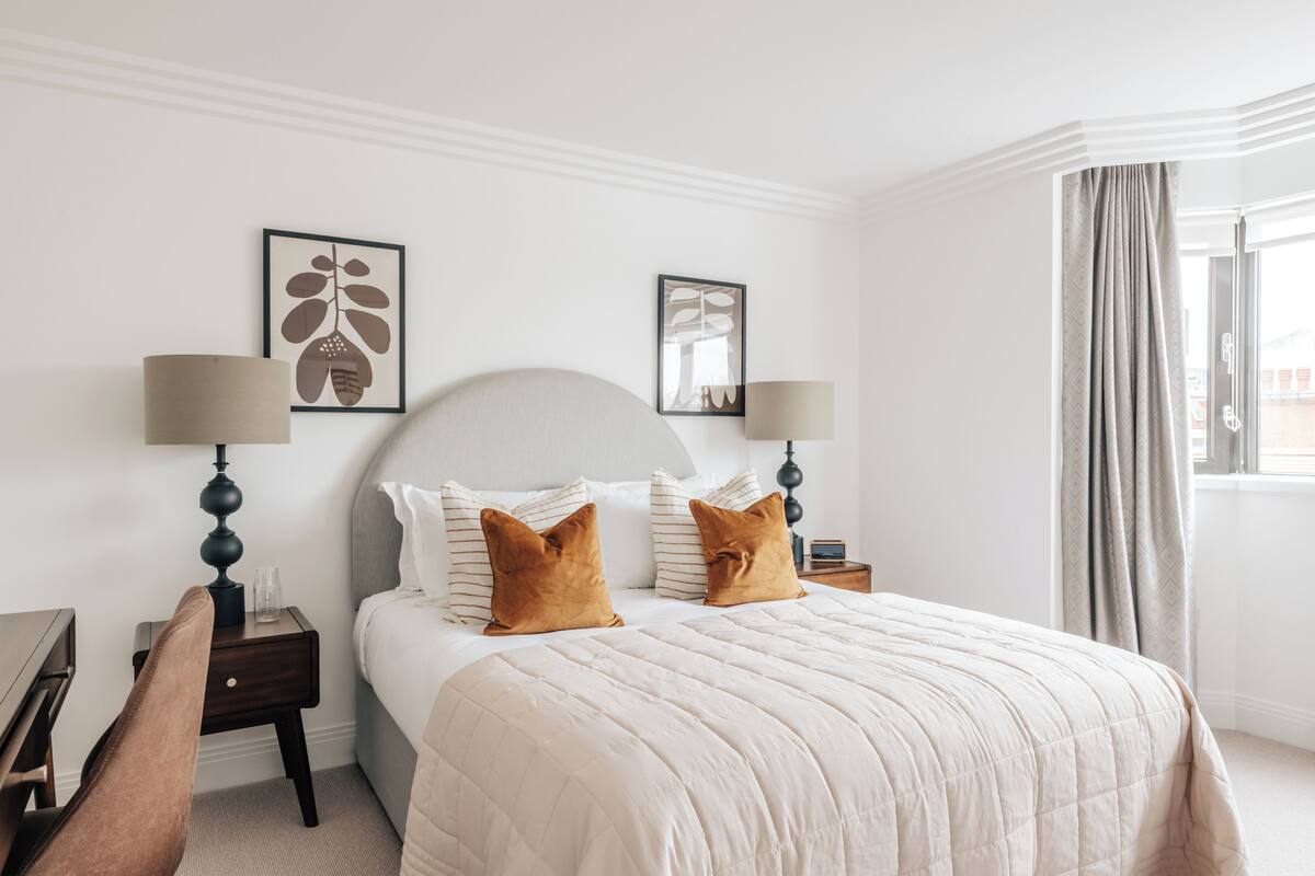 Une chambre d’hôtel avec un lit, deux tables de chevet, une chaise et des œuvres d’art accrochées aux murs.
