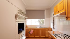 Una cocina con armarios de madera, estufa a gas, refrigerador blanco y ventana con vista a follaje.