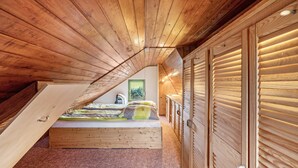 A wooden sloped ceiling bedroom with a bed, wooden wardrobe, and a painting on the wall. - Cozy Kirschallee Cottage with Mountain View, Private Terrace & Shared Garden (Hohnstein)