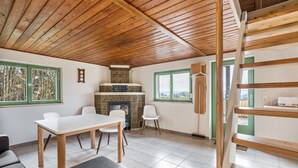 A room with a wooden ceiling, a fireplace, a dining table with chairs, and a staircase. - Cozy Kirschallee Cottage with Mountain View, Private Terrace & Shared Garden (Hohnstein)