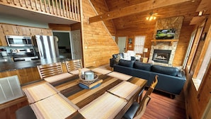 A cozy cabin interior with a dining area, kitchen, and living room. - Mountaintop Memories-Hot Tub, Game Room, Pet Friendly, Near Grayson Highlands (Grassy Creek)