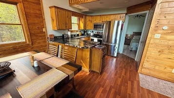 L’intérieur d’un chalet en bois comprend une cuisine, un coin repas et offre une vue sur l’extérieur.