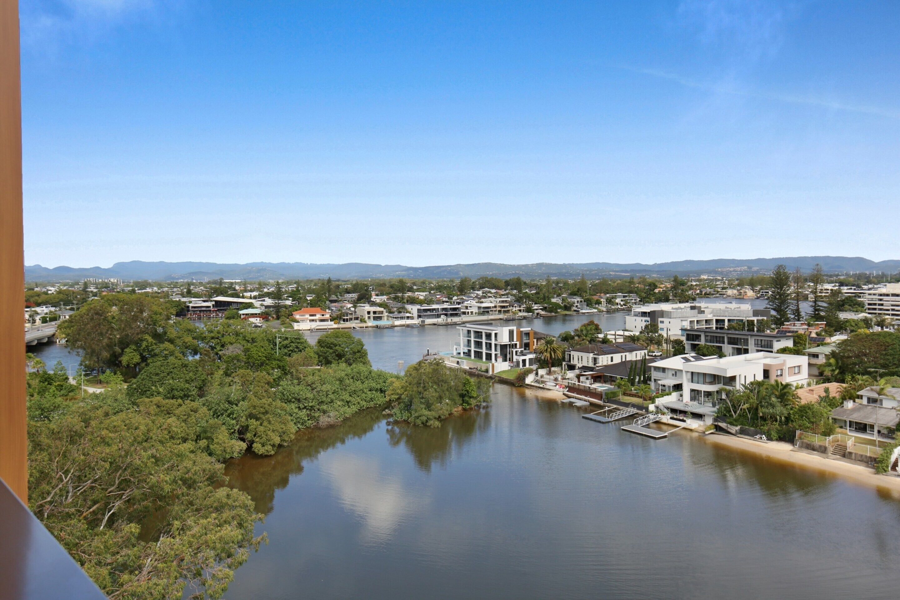 A riverside residential area with modern houses, a dock, and a bridge.