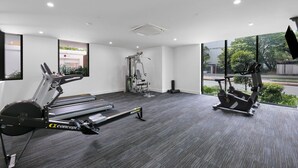 A gym with treadmills, a stationary bike, and a weight machine. - Surfers Paradise 2-bed Flat With Luxury Amenities (Gold Coast)