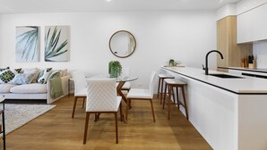 A modern kitchen with a white countertop, wooden cabinets, and a black faucet. - Surfers Paradise 2-bed Flat With Luxury Amenities (Gold Coast)