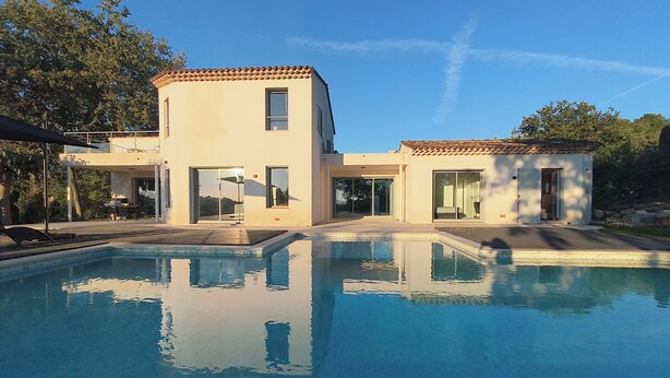 Ein modernes Haus mit Swimmingpool, großen Fenstern und einer Terrassenfläche.