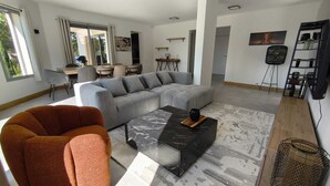 Ein modernes Wohnzimmer mit einem grauen Ecksofa, einem schwarzen Couchtisch und einem roten Sessel.