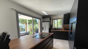 Eine moderne Küche mit einer Holz Arbeitsplatte, schwarzen Schränken und einem großen Fenster mit Blick auf Grünflächen.