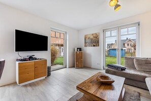 Una sala de estar moderna con televisor de pantalla plana, un mueble de madera y un sofá.