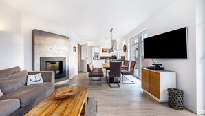 A modern living room with a fireplace, a dining area, and a TV mounted on the wall. - Holiday Home 'Treibholz' with Private Terrace, Private Garden and Wi-Fi (Dassow)