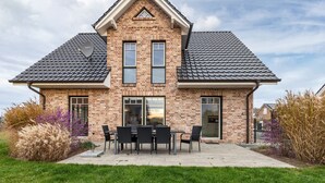 A two-story brick house with a gabled roof, a patio with outdoor furniture, and a well-maintained lawn. - Holiday Home 'Treibholz' with Private Terrace, Private Garden and Wi-Fi (Dassow)