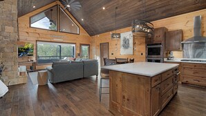 A spacious kitchen with wooden cabinetry, a large island, and a stone fireplace. - Great Trails Lodge - Blue Ridge (Epworth)