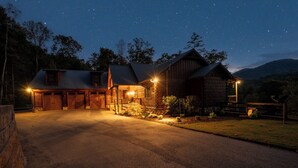 A rustic cabin with a stone exterior, multiple garage doors, and a well-lit driveway at night. - Great Trails Lodge - Blue Ridge (Epworth)