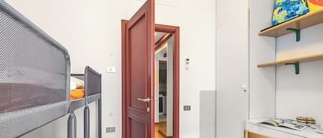 Una habitación pequeña con literas, un escritorio de madera y una puerta que da a otra habitación.