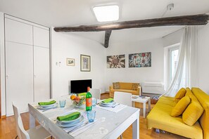 A dining area with a table set for two, a sofa, and artwork on the walls. - Bogliaco Lake Front (Gargnano)