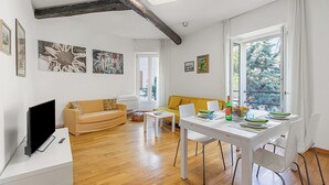 Un salon moderne comprenant un canapé, une table à manger avec des chaises, un téléviseur à écran plat et des œuvres d’art accrochées aux murs.
