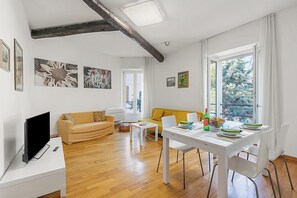 Un soggiorno moderno con divano, tavolo da pranzo con sedie, televisore a schermo piatto e opere d'arte alle pareti.