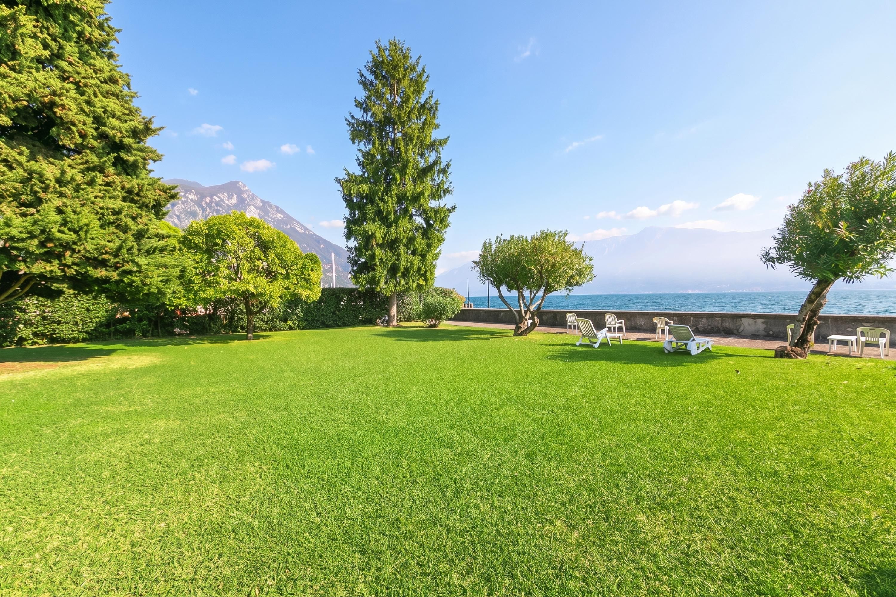 A well-maintained grassy area with a view of the sea and mountains in the background.
