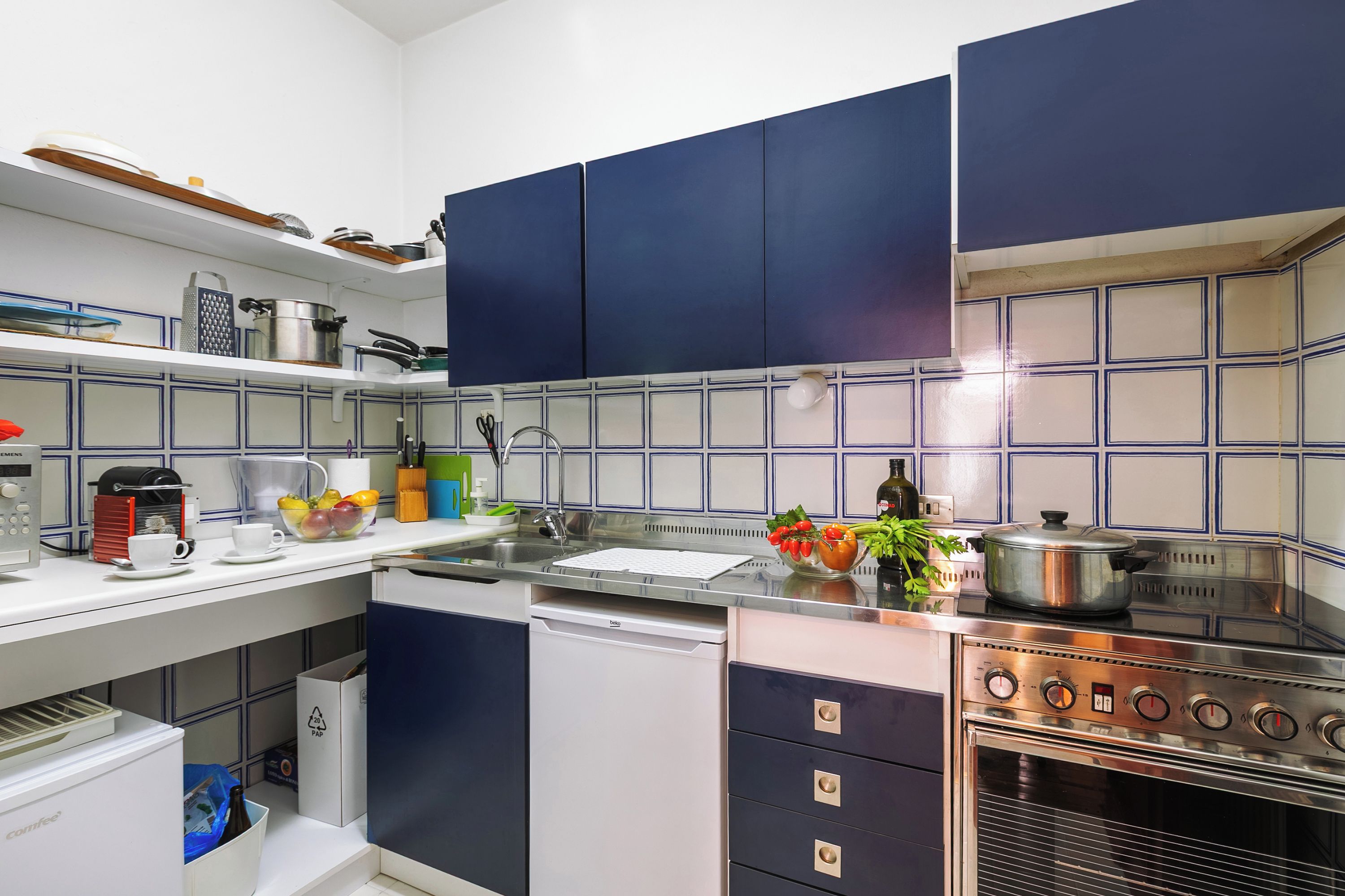 A modern kitchen with blue cabinets, a stainless steel stove, and a dishwasher.