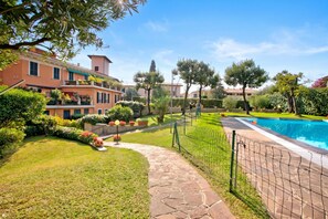 Zona residencial con piscina, césped cuidado y diversas plantas.