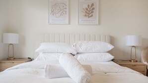 A neatly made bed with white linens, two framed artworks on the wall, and bedside lamps on wooden nightstands. - Ground Level 1-bed: Courtyard & Alfresco Dining (Canberra)