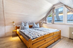 A bedroom with a wooden bed, a window with curtains, and a radiator.