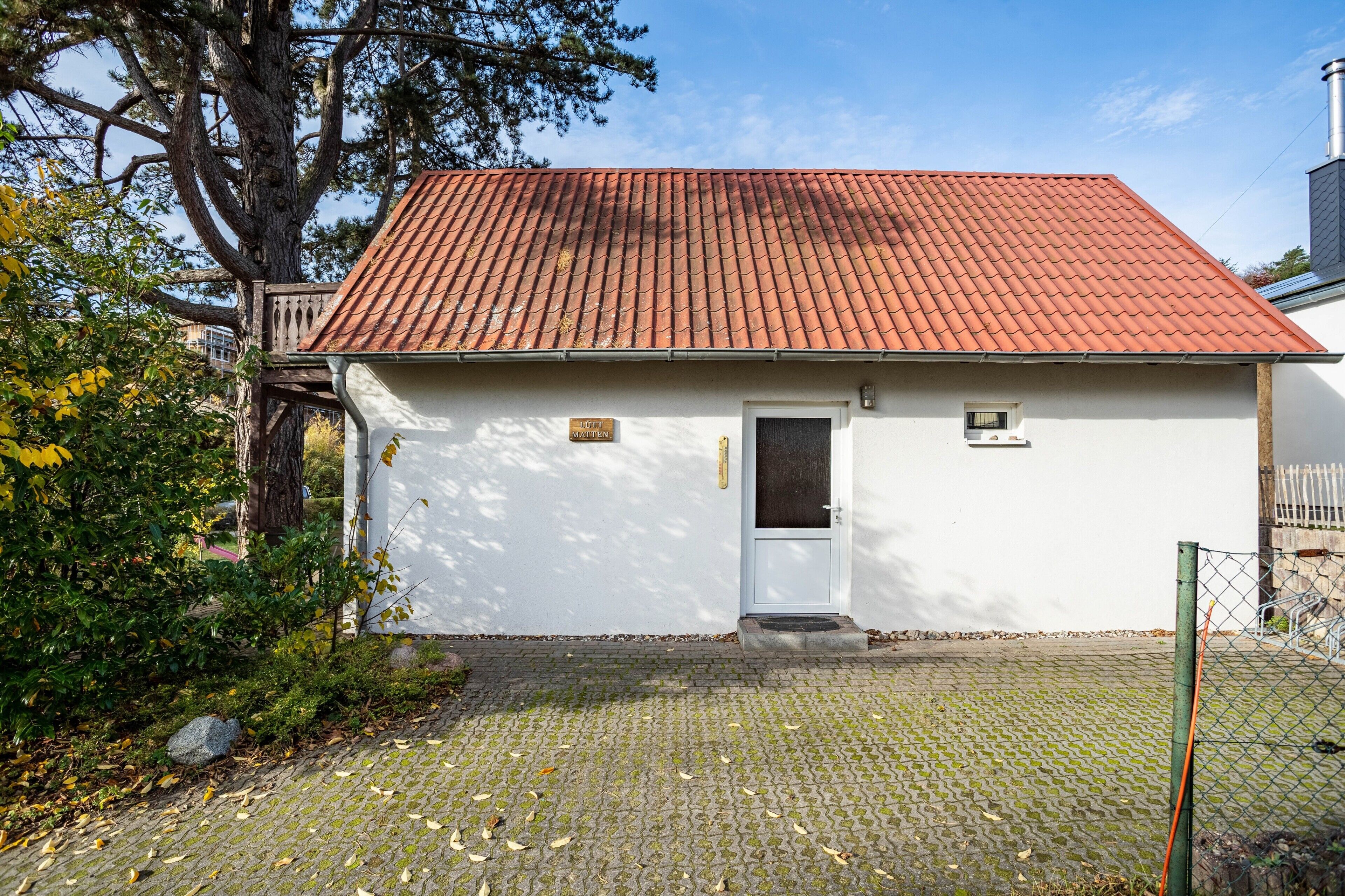 A small white building with a red-tiled roof, a door, and a small window.