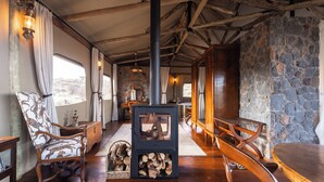 Ein rustikales Interieur mit einer Steinwand, Holzmöbeln, einem Kamin und einem großen Fenster.