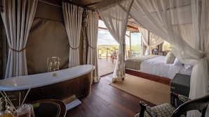 Ein Schlafzimmer mit einem großen Bett, einer Badewanne und Blick ins Freie.