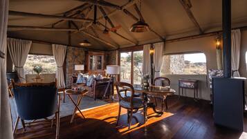 A tented room with wooden floors, a dining table, chairs, a sofa, and a fireplace.