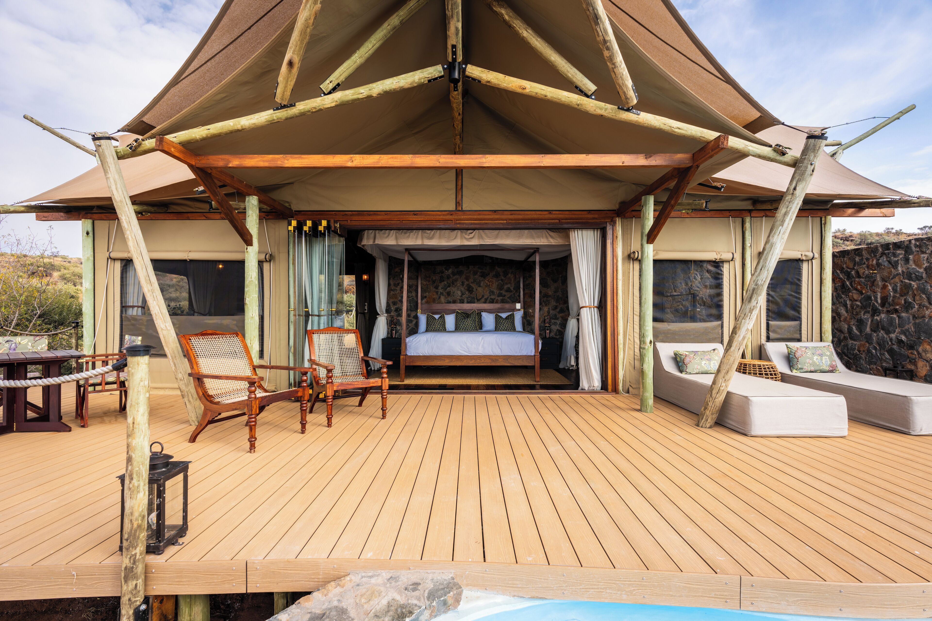 A wooden deck with a bed, two sofas, and a table.