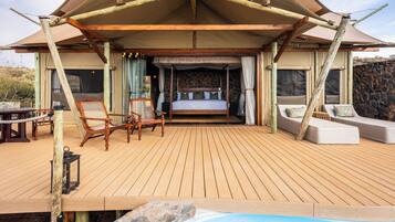 A wooden deck with a bed, two sofas, and a table.