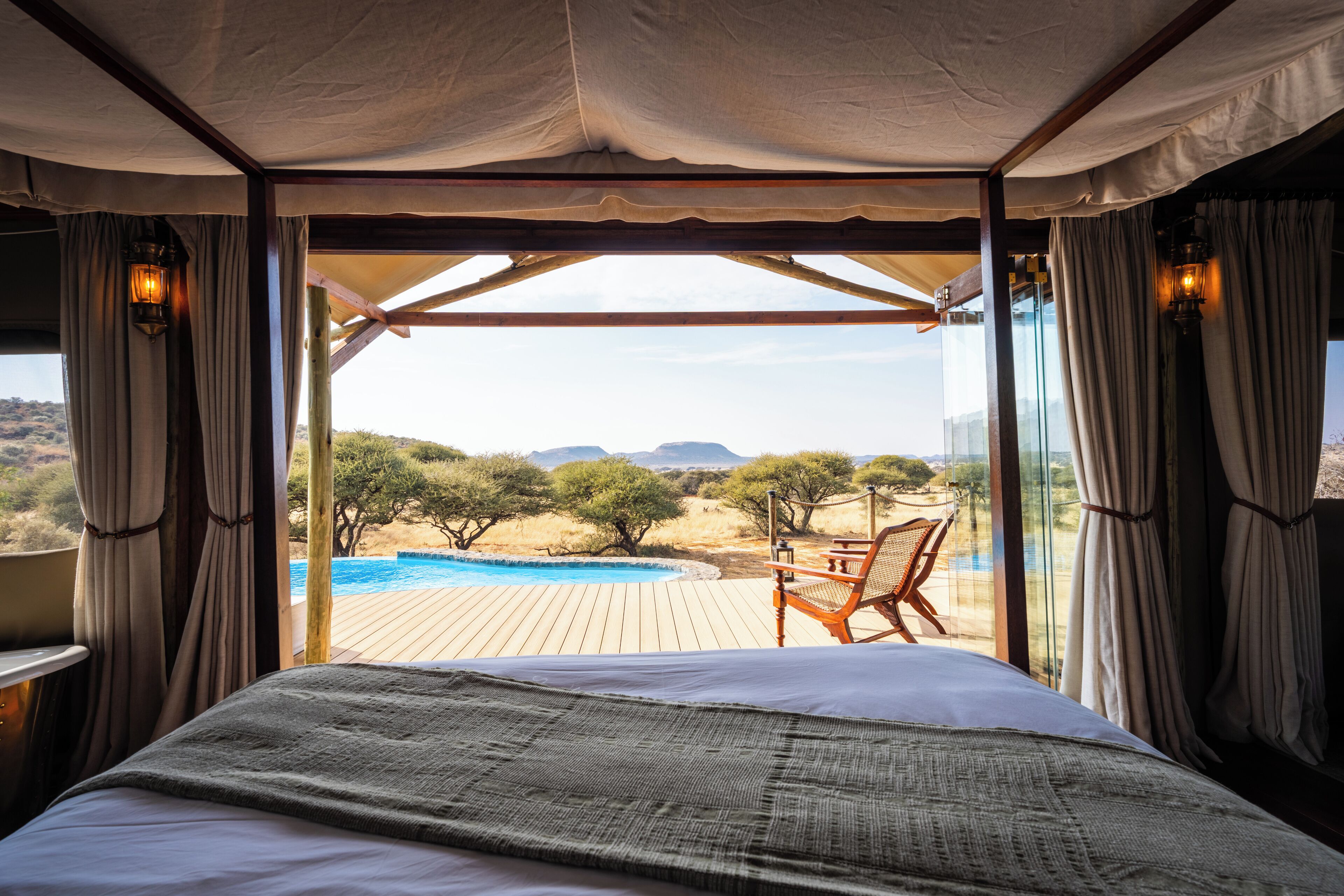 Une chambre avec un grand lit, une vue sur une piscine et un espace extérieur avec une chaise.