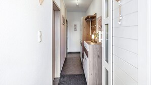 A narrow hallway with a wooden cabinet, a mirror, and a door on the right. - Holiday Home 'Radlerrast' with Private Garden and Wi-Fi (Weißenfels)